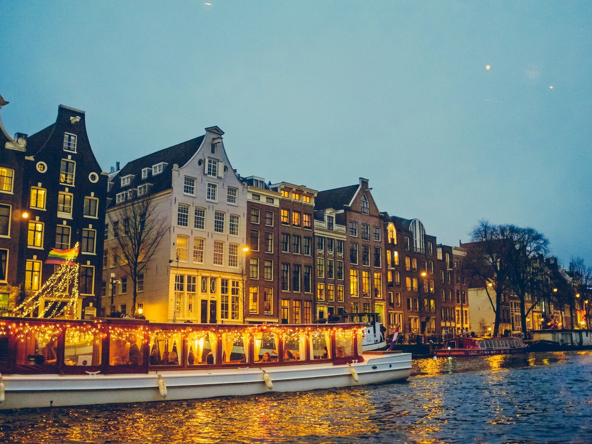 boat sailing on river near lighted houses and trees