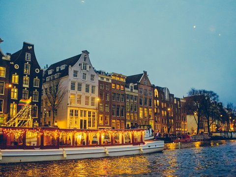 boat sailing on river near lighted houses and trees