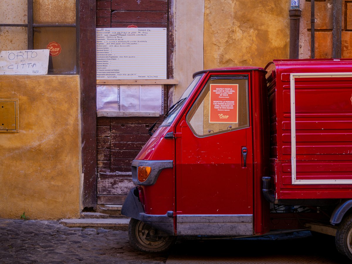 A small red truck parked in front of a building