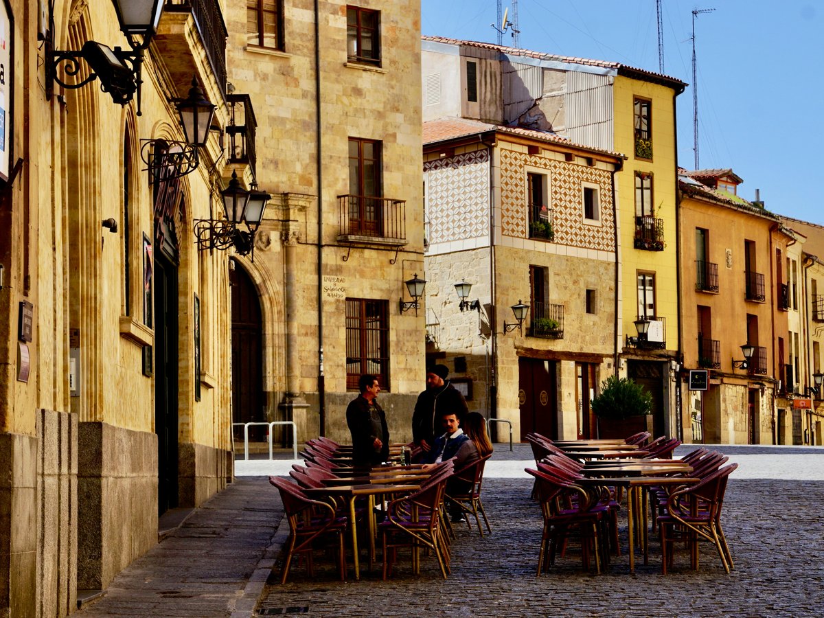 man and woman sitting on brown wooden chairs near brown concrete building during daytime