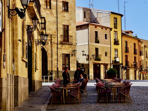 man and woman sitting on brown wooden chairs near brown concrete building during daytime