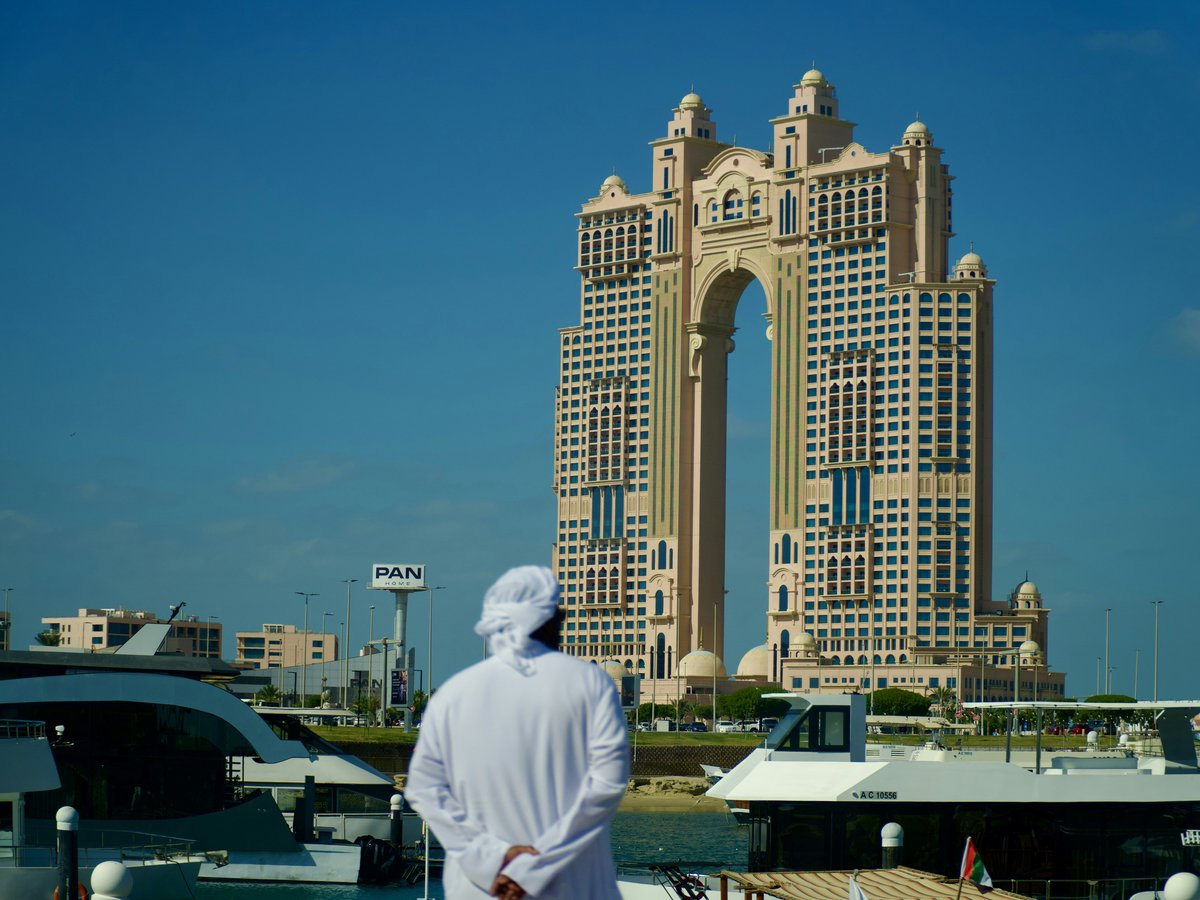 Man in traditional clothing looks at modern skyscraper