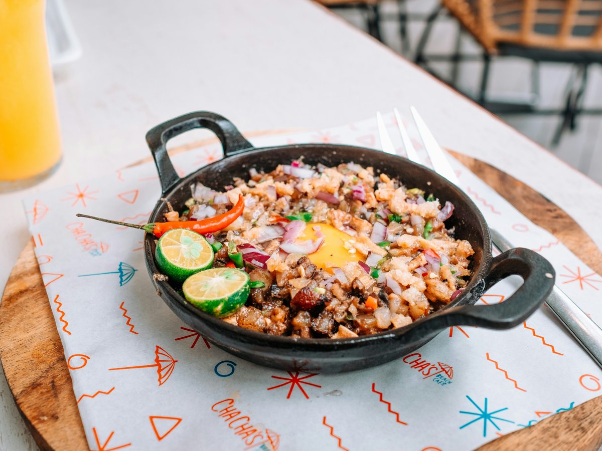a pan of food on a table with a glass of orange juice