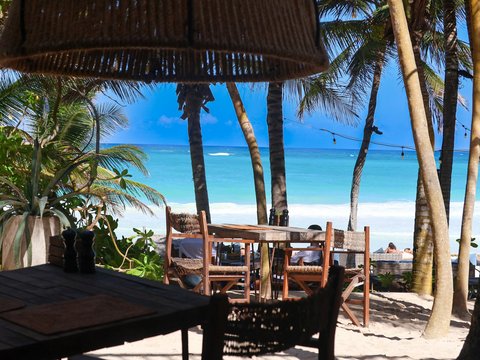 a table and chairs on a beach with palm trees