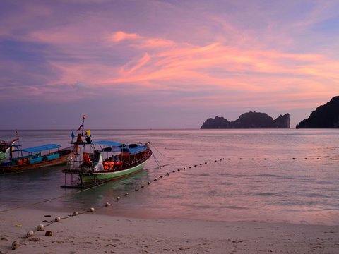 green boat on beach during sunset