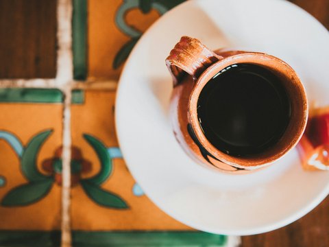 brown ceramic mug with coffee on white ceramic saucer