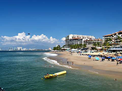 Sunny beach with resort buildings and ocean waves