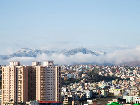 Cityscape with distant mountains shrouded in clouds.