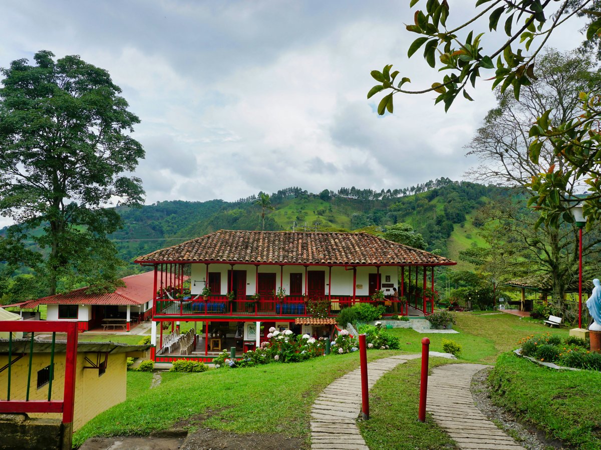 brown wooden house near green trees under white clouds during daytime