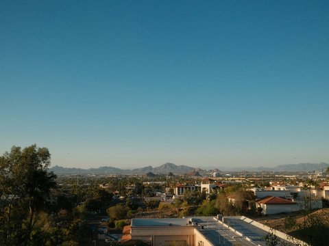 Cityscape with mountains under a clear blue sky.