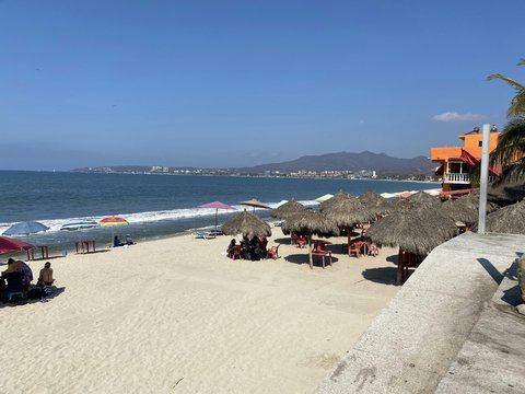 a sandy beach with umbrellas and people sitting on it