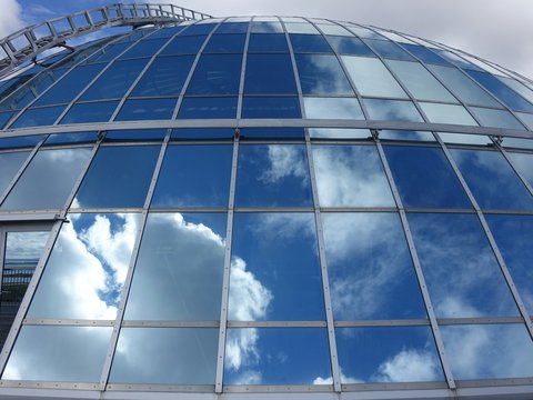 a large glass building with a sky reflection in it