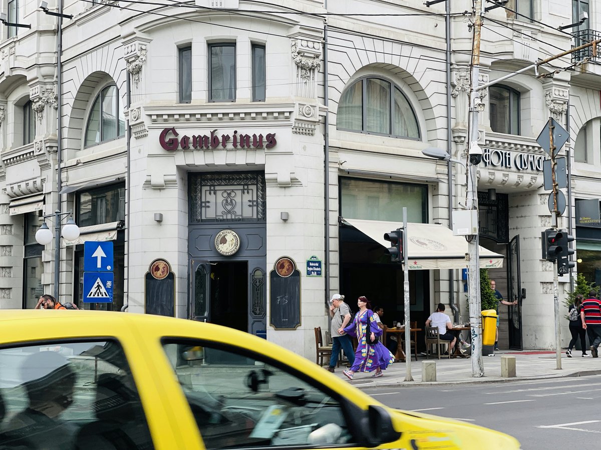 a yellow taxi driving past a tall white building