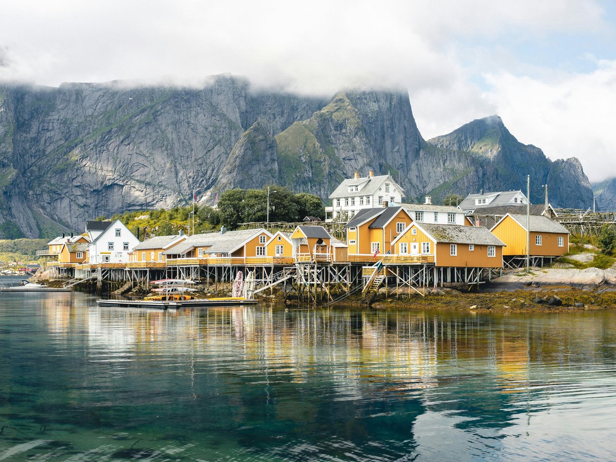 brown and white wooden houses near body of water and mountain during daytime