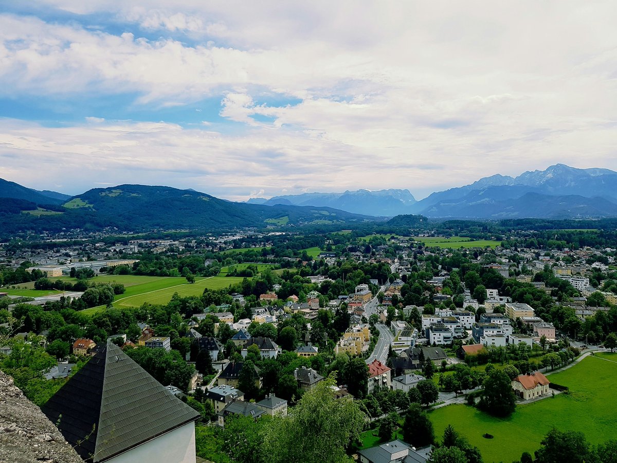 a scenic view of a town with mountains in the background