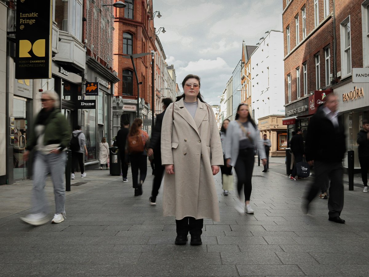a man in a trench coat walking down a street