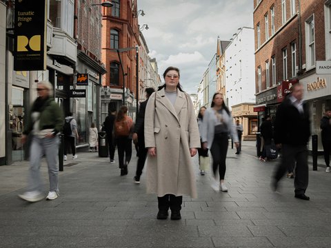 a man in a trench coat walking down a street