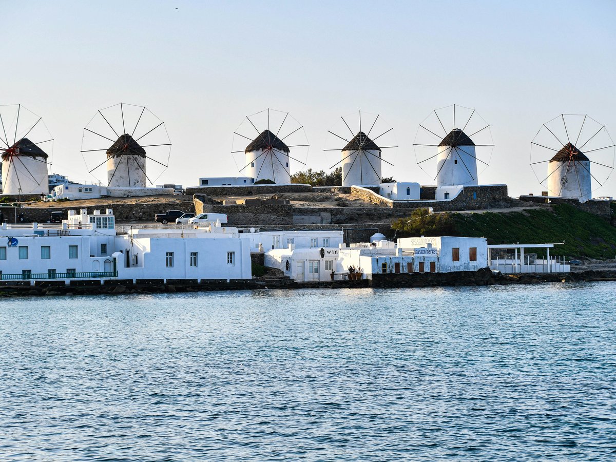 a row of windmills sitting on top of a hill next to a body of