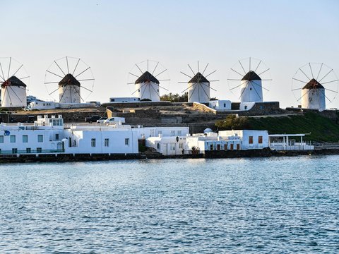 a row of windmills sitting on top of a hill next to a body of