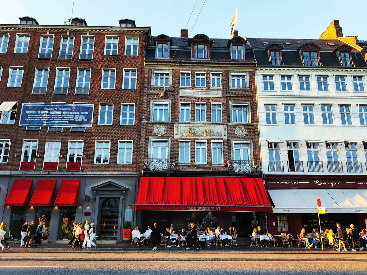 People dining outside buildings with red awnings