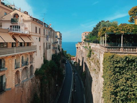 a street with a car driving down it next to a cliff