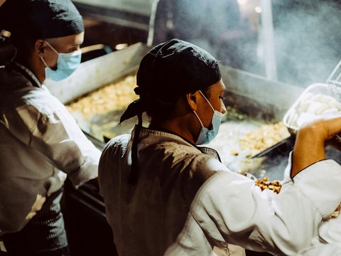 a man and a woman cooking food in a kitchen