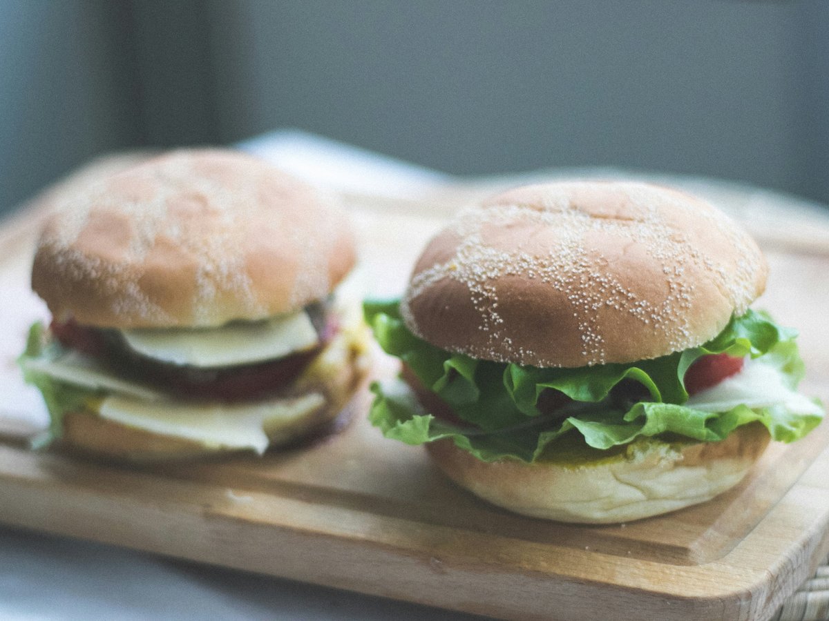 two burgers on brown wooden chopping board
