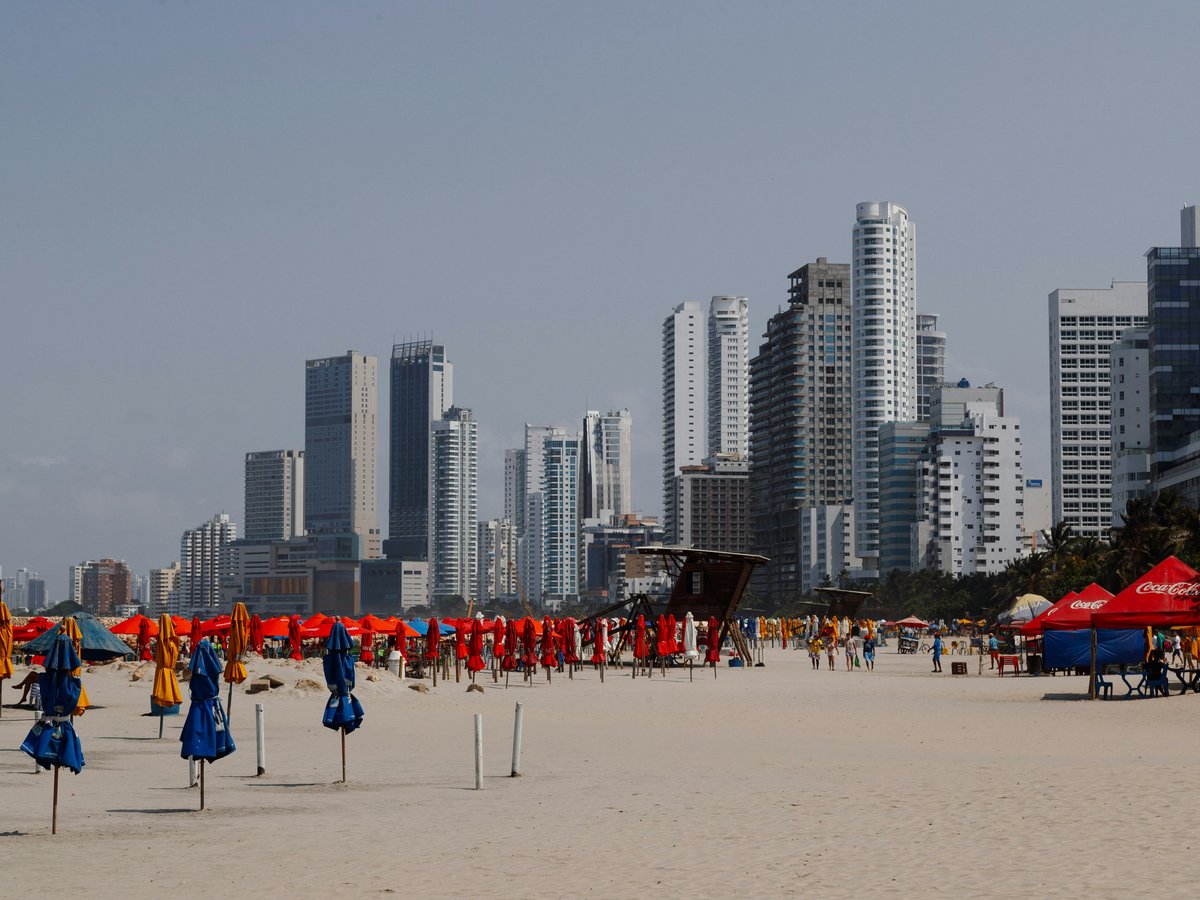 a beach with a lot of umbrellas and buildings in the background