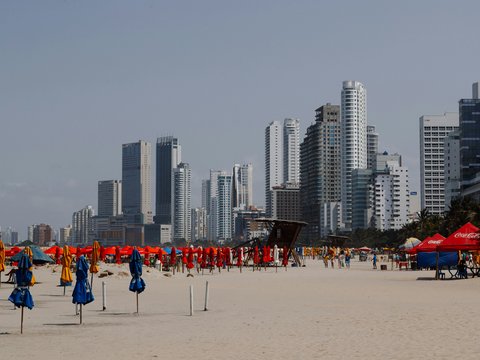 a beach with a lot of umbrellas and buildings in the background