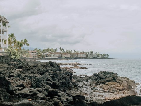 a white building sitting on top of a rocky beach