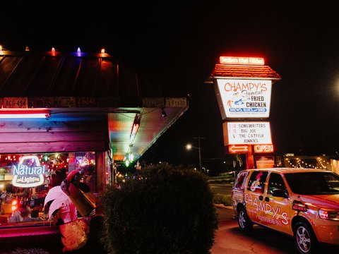 a street with a car and a building with signs and lights