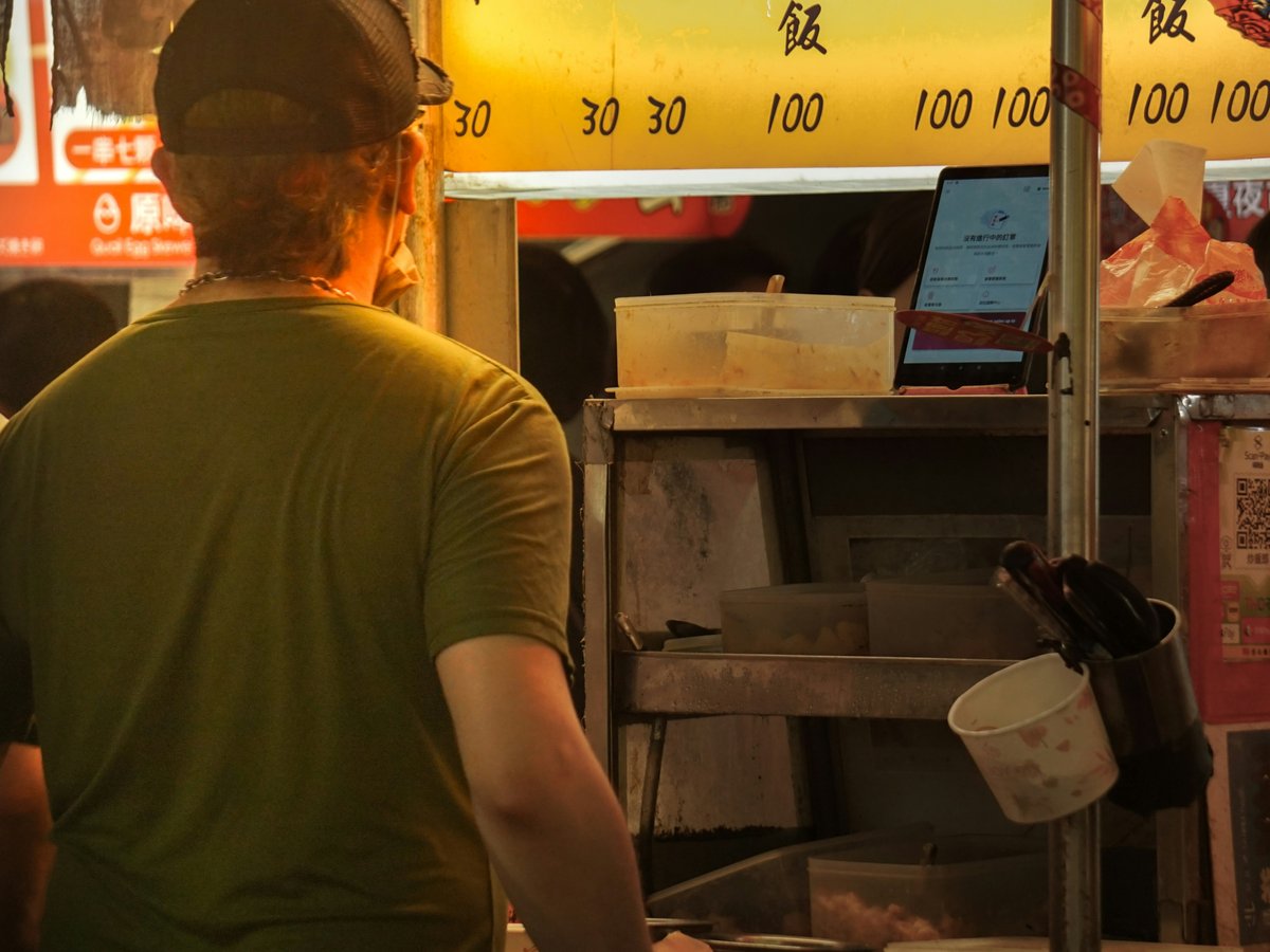 A group of people standing around a food stand