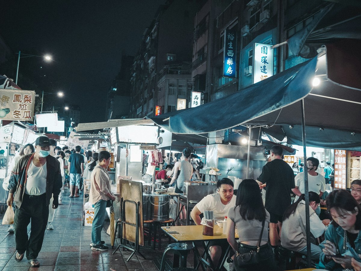 A group of people walking down a street at night