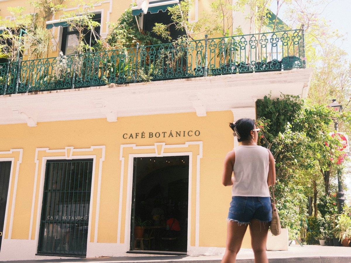 A woman standing in front of a yellow building