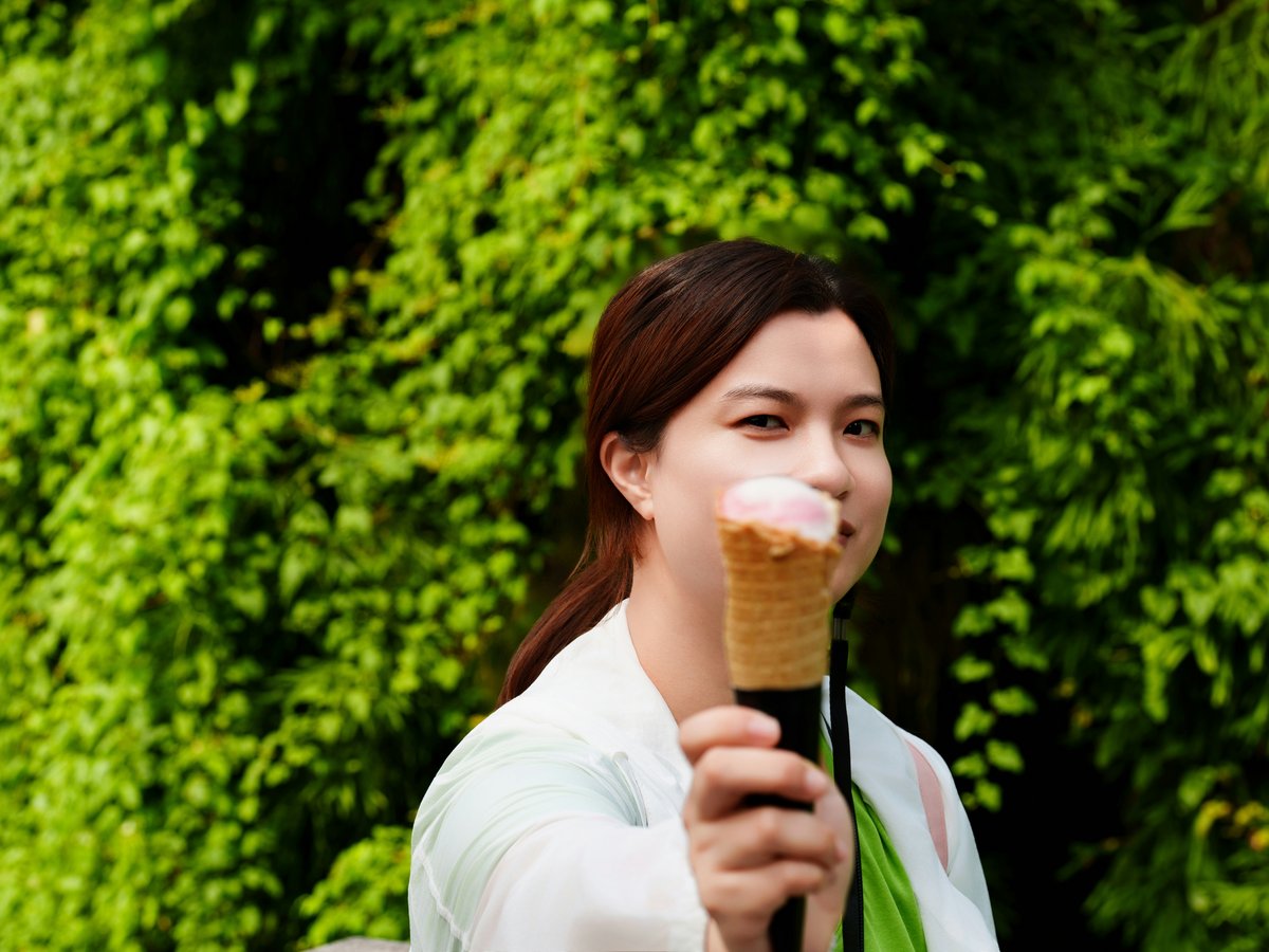 Woman holding an ice cream cone in front of greenery