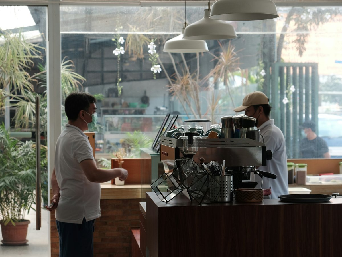 man in white polo shirt standing in front of counter