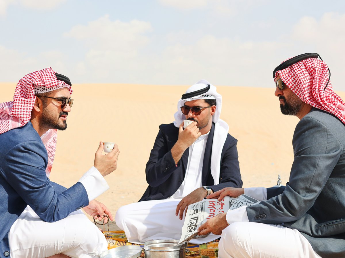 A group of men sitting on top of a sandy beach