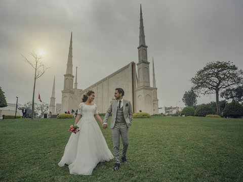 a bride and groom walking in front of a church