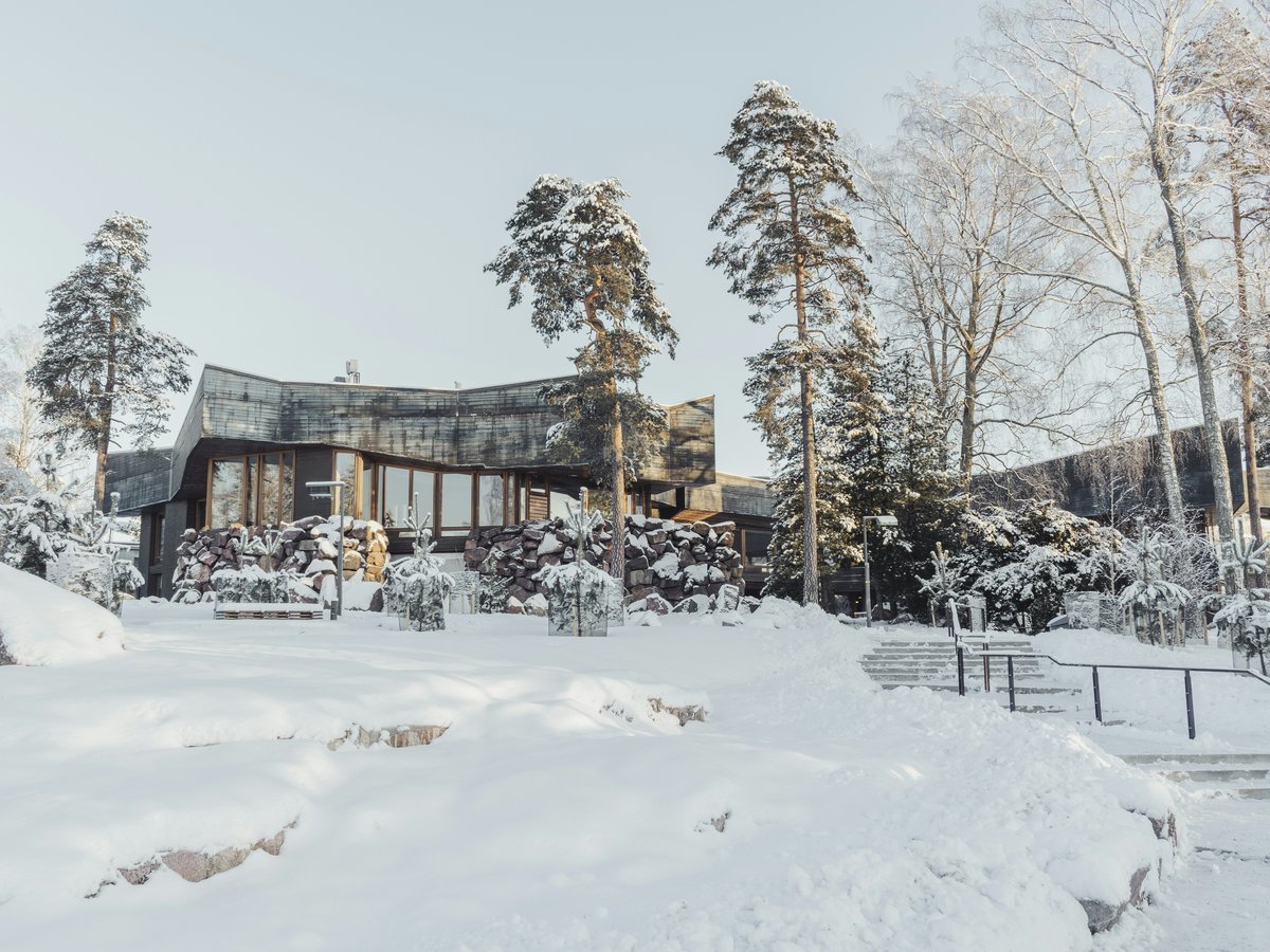 a house in the middle of a forest covered in snow