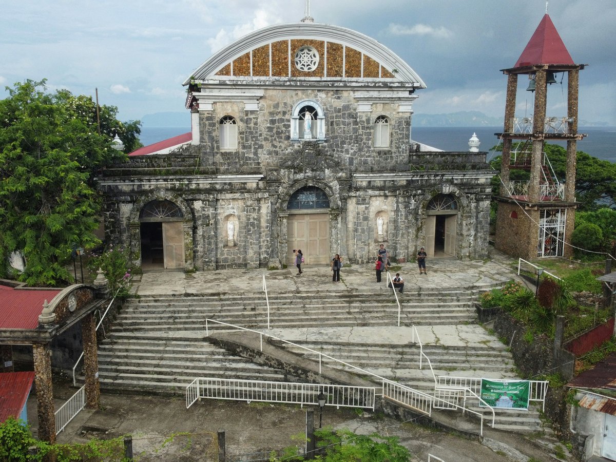 an old church with a steeple next to a body of water