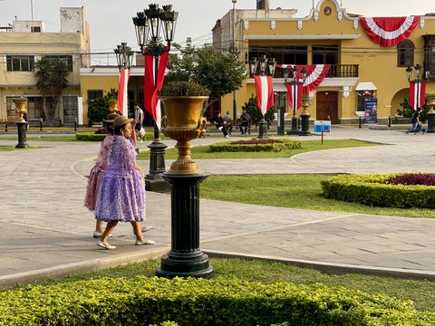 Two women stroll through a colorful plaza.
