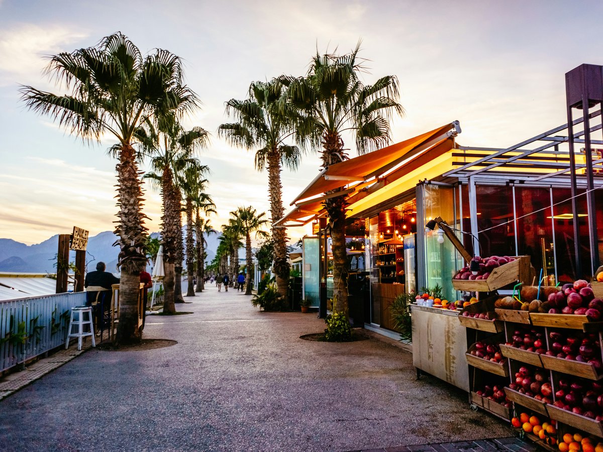 a fruit stand on the side of a road with palm trees