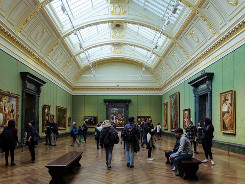 a group of people standing in a museum looking at paintings