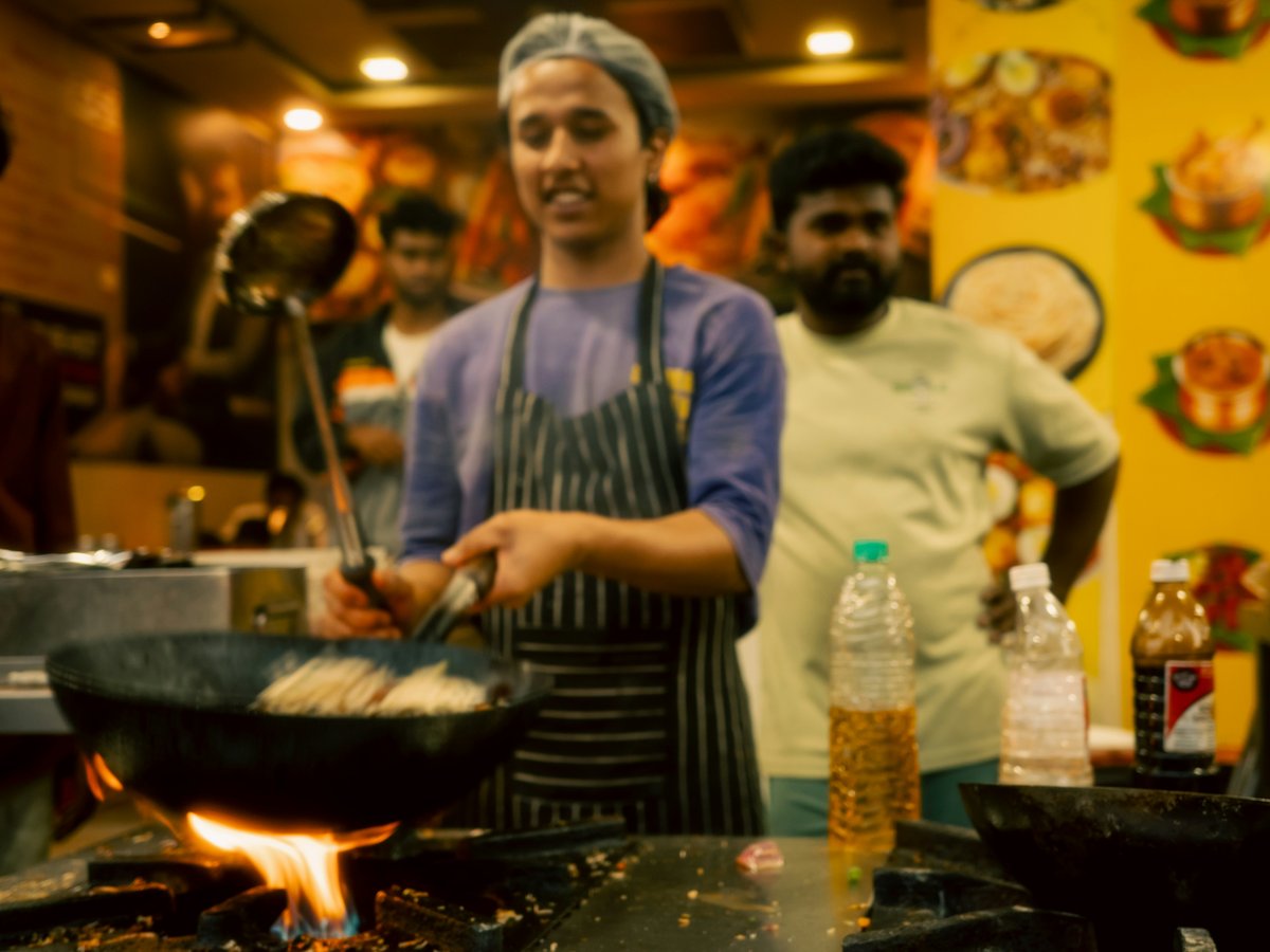 A chef cooking food in a wok on a wok
