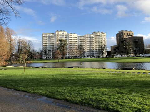 green grass field near city buildings under blue sky during daytime