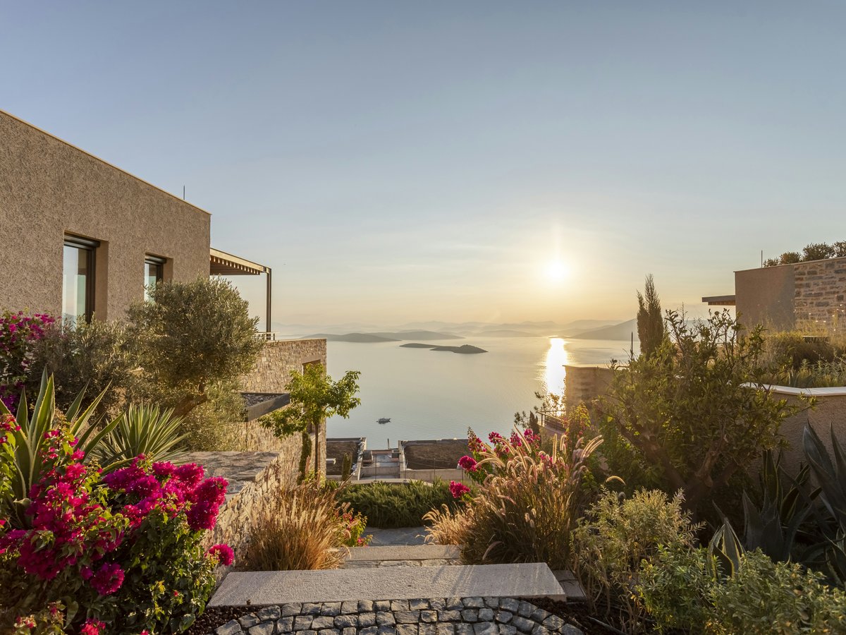 the sun is setting over the water from a house