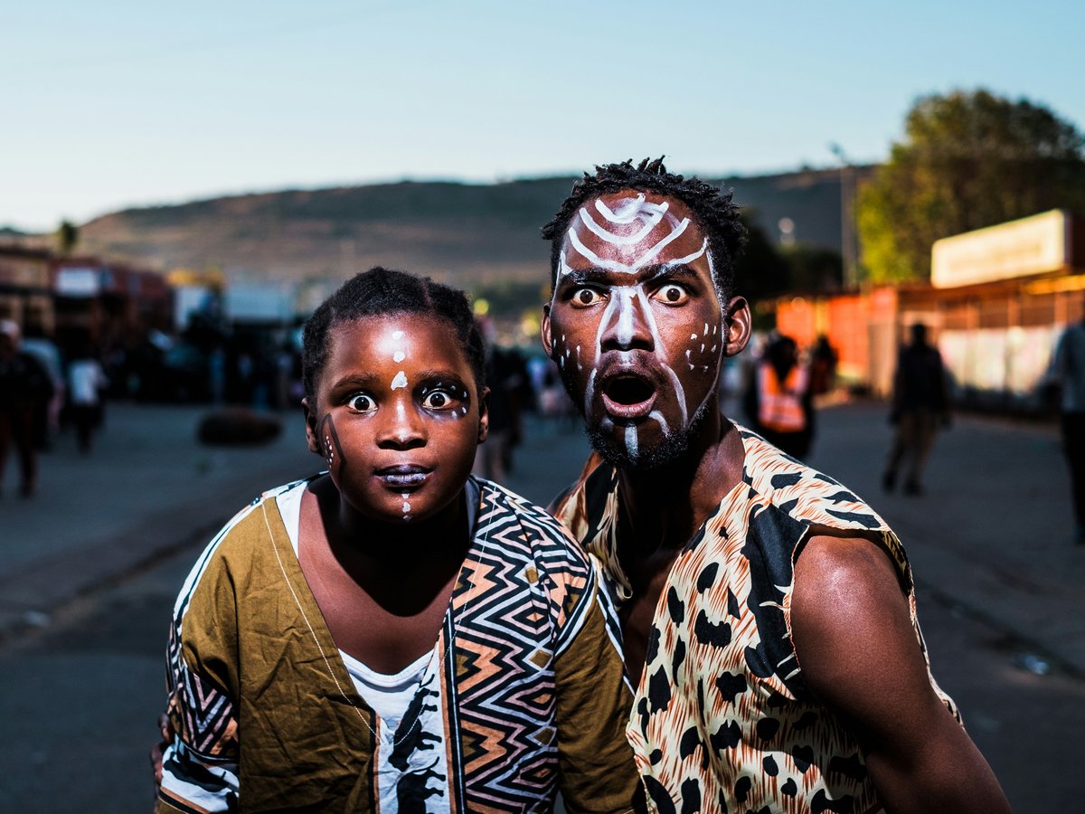 two people with face paints taking photo in street