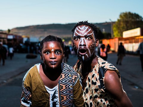 two people with face paints taking photo in street