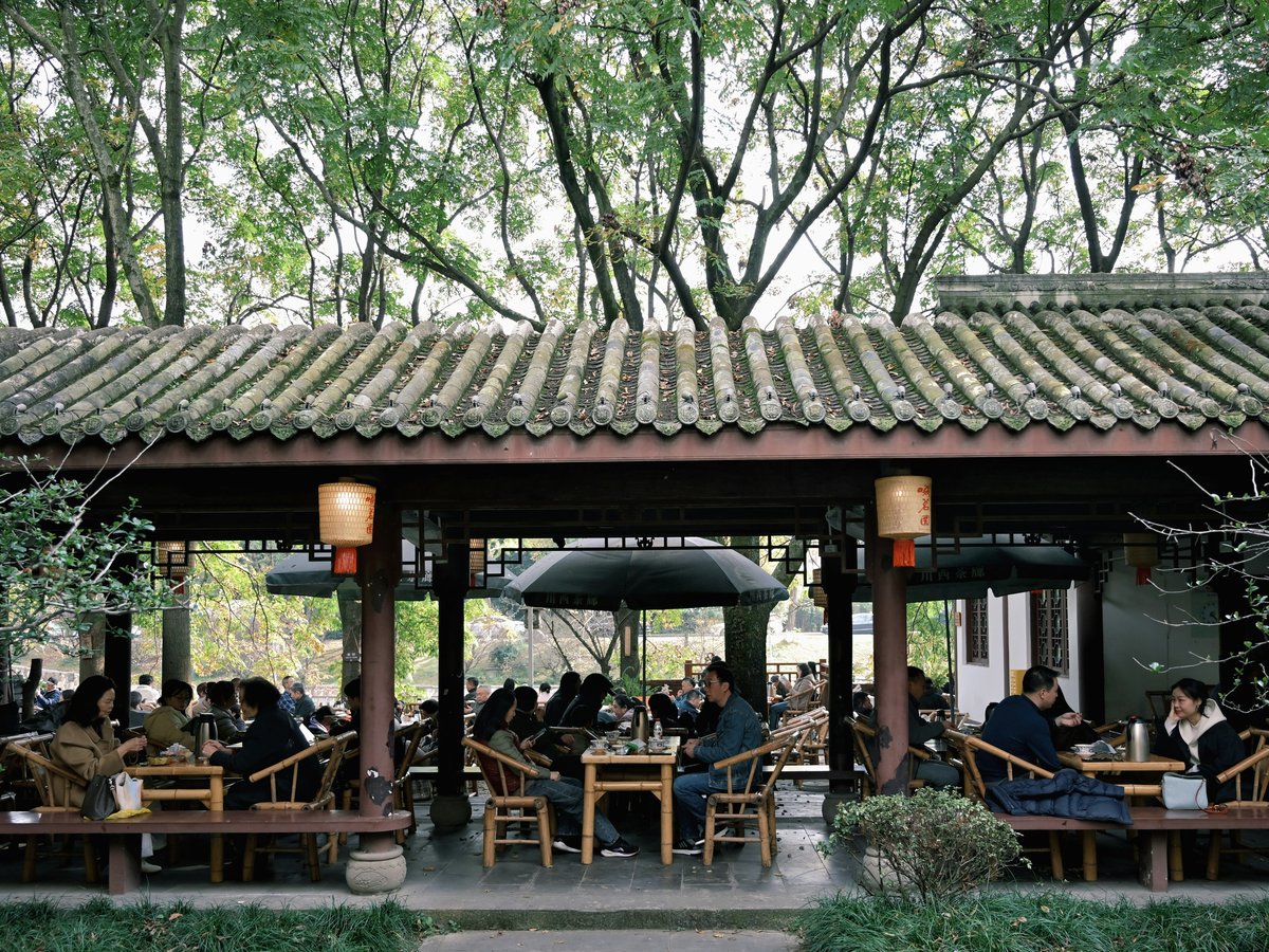 People seated at tables under a covered outdoor seating area