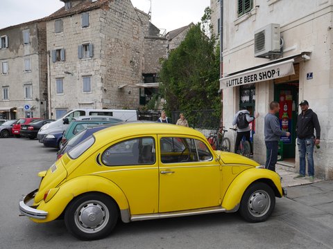 yellow volkswagen beetle parked beside brown concrete building during daytime